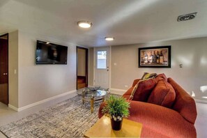 A living room with a flat-screen TV, a glass coffee table, a red sofa, and a framed picture on the wall. - Wine Country 3BR Mountainview Oregon Wine Country (Dundee)