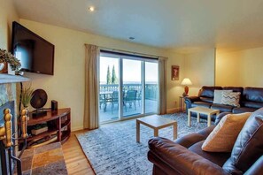 A living room with a sofa, a TV, a coffee table, and a balcony with outdoor furniture. - Wine Country 3BR Mountainview Oregon Wine Country (Dundee)