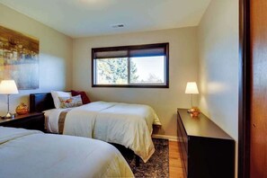 Een hotelkamer met twee bedden, een raam met zonwering, een nachtkastje met een lamp en een dressoir met een lamp.