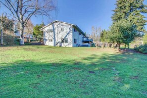 Une maison à deux étages avec une véranda à l’avant et un jardin à l’arrière.