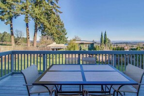 Une terrasse avec une table et des chaises, donnant sur un quartier résidentiel bordé d’arbres et de maisons.