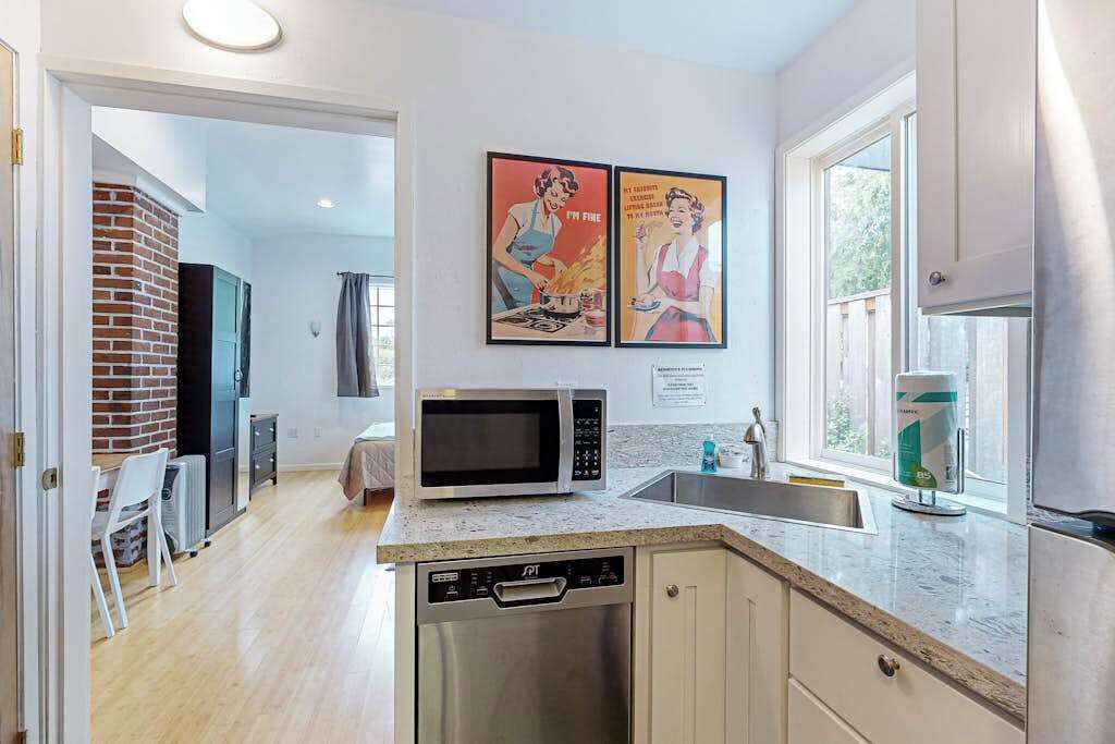 A modern kitchen with a microwave, dishwasher, and a window with a view.