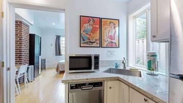 A modern kitchen with a microwave, dishwasher, and a window with a view.