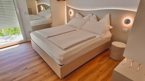 A modern bedroom with a large bed, bedside lamps, and a view through a window. - Residenza Francesca Luxury Suite (Riva del Garda)