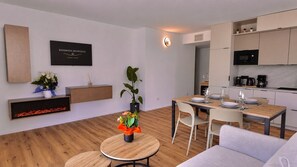 A modern living room with a dining area, a fireplace, and a kitchen with built-in appliances. - Residenza Francesca Luxury Suite (Riva del Garda)