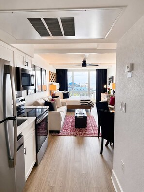 Habitación de hotel moderna con kitchenette, una cama, un sofá y vistas a la ciudad.
