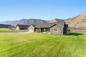 Ein zweistöckiges Haus mit Garage, einem gepflegten Rasen und einem Bergpanorama.