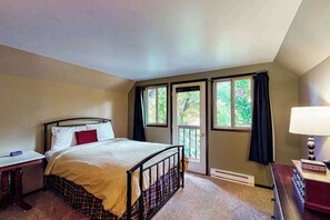 Een slaapkamer met een bed, bureau, lamp en raam met gordijnen.