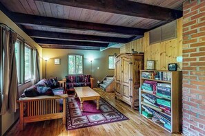 A cozy room with a wooden ceiling, a sofa, a coffee table, a bookshelf, and a staircase. - 3BR Mountainview Dog Friendly (Leavenworth)
