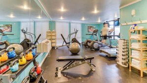 Ein Fitnessstudio mit Trainingsgeräten, Laufband und einer trainierenden Person.