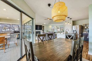 Une cuisine moderne avec un coin repas, de grandes fenêtres et une vue sur les arbres.