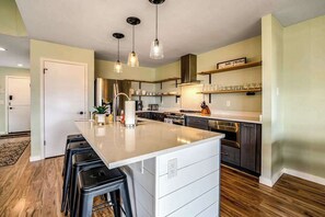 A modern kitchen with a central island, bar stools, pendant lighting, and stainless steel appliances. - Renovated 3BR Mountainview - Pool - Hot Tub (Manson)