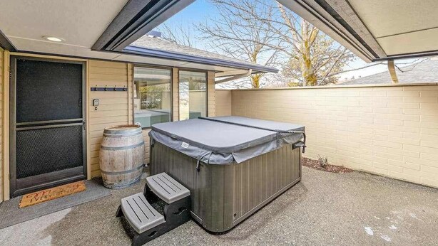Ein mit Deckel abgedecktes Whirlpool, ein Holzfass und ein kleiner Trittschemel vor einem Gebäude.