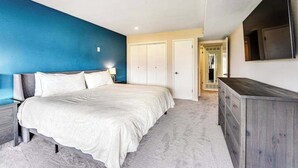 Ein Schlafzimmer mit einem Bett, einem Schminktisch, einem Fernseher und einem Kleiderschrank.