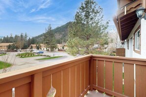 A residential area with a wooden balcony overlooking a street and a mountain backdrop. - Downtown 1BR Mountainview 2nd-Floor - Balcony (Leavenworth)