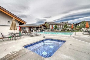Zona de piscina de hotel con jacuzzi, sillones de descanso y sombrillas.