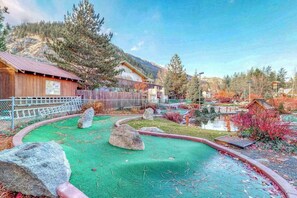 A rustic cabin with a fenced yard, a small pond, and a mountainous backdrop. - Downtown 1BR Mountainview 2nd-Floor - Balcony (Leavenworth)