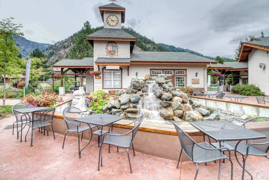 A building with a clock tower, outdoor seating area, and a waterfall feature.