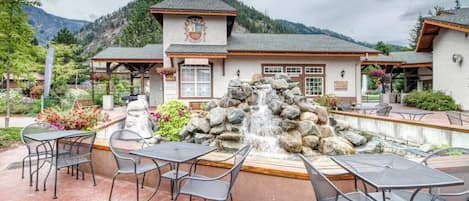 A building with a clock tower, outdoor seating area, and a waterfall feature.