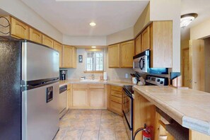 A kitchen with wooden cabinets, a stainless steel refrigerator, a microwave, and a dishwasher. - Downtown 1BR Mountainview 2nd-Floor - Balcony (Leavenworth)