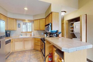 Una cocina con armarios de madera, microondas, estufa y lavavajillas.