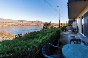 A patio with outdoor furniture overlooking a lake, a grassy area, and a view of distant hills. - 2BR Lakeview - Patio - Washer/Dryer (Chelan)