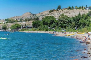 A coastal area with a beach, boats, and buildings on a hillside. - 2BR Lakeview - Patio - Washer/Dryer (Chelan)