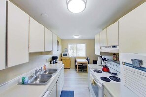 Uma cozinha compacta com pia, fogão e um espaço de refeições com mesa e cadeiras.