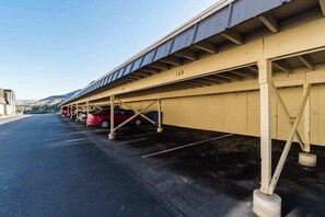 Área de estacionamento coberta com vários carros estacionados sob uma estrutura.