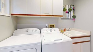 Ett tvättrum med två vita tvättmaskiner från Whirlpool och ett handfat.