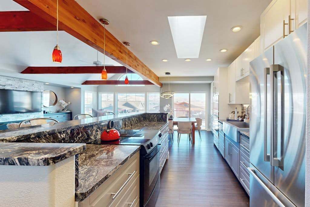 A modern kitchen with a large island, stainless steel appliances, and a skylight.