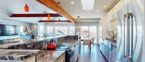 A modern kitchen with a large island, stainless steel appliances, and a skylight.