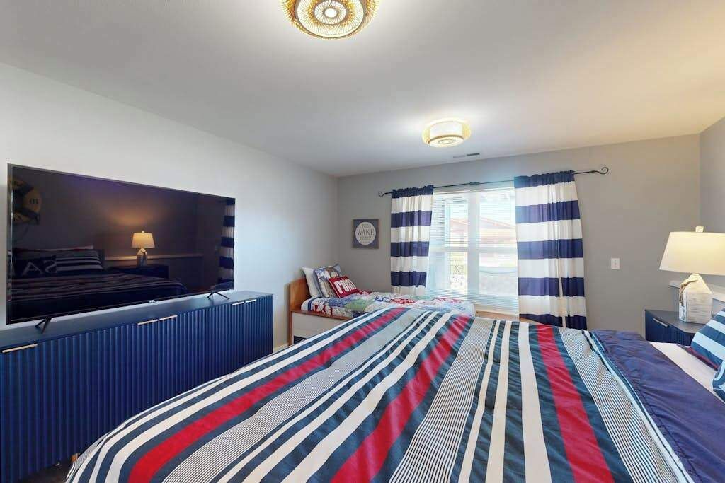 Une chambre d’hôtel avec un lit, une télévision, un bureau et une fenêtre avec des rideaux.