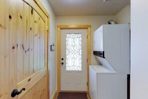 Ein schmaler Flur mit einer Holztür und einem weißen Kühlschrank auf der rechten Seite.