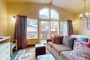 A cozy living room with a sofa, ottoman, and a view through large windows. - 1 BR condo located in Icicle Village, Leavenworth (Leavenworth)