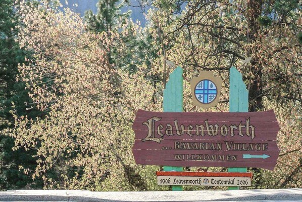 Uma placa de madeira com o texto 'Leavenworth Bavarian Village Wilkomen' e uma seta apontando para a direita.