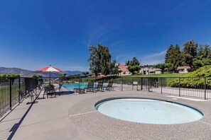 A pool area with a circular hot tub, lounge chairs, and a view of a mountain range. - 2BR Lakefront Condo - Pool - Patio - Tennis (Chelan)