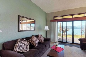 Ein Hotelzimmer mit großem Fenster, einer Couch, einem Couchtisch und einer Lampe.
