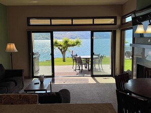 Ein Zimmer mit Seeblick, einem Essbereich inklusive Stühle und Tisch sowie einem Sofa.