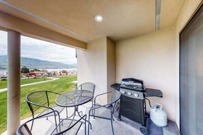 A balcony with a grill, a table, and chairs. - Bright 1BR Lakefront - Patio - Pool (Chelan)