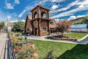 A wooden structure with a bell tower, surrounded by a well-maintained lawn and flower beds. - Bright 1BR Lakefront - Patio - Pool (Chelan)
