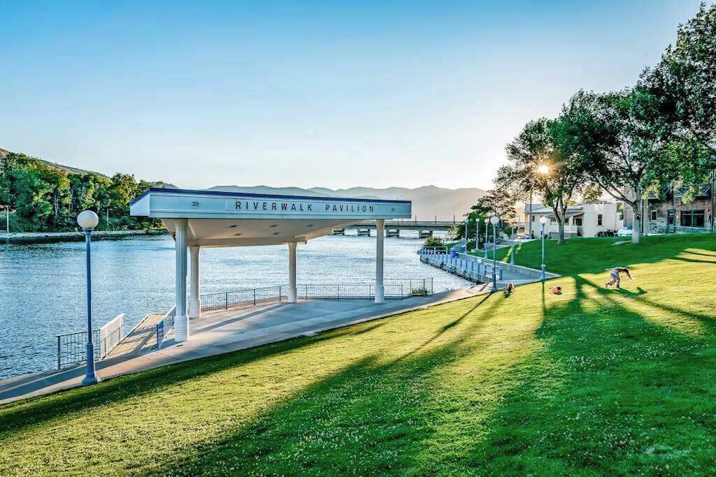 Un pabellón llamado 'Riverwalk Pavilion' con vistas a un río y montañas al fondo.