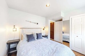 A bedroom with a bed, bedside tables, a wall-mounted light, a door, and a closet. - Bright 1BR Lakefront - Patio - Pool (Chelan)