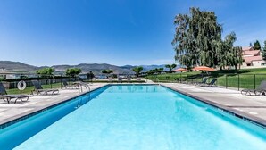 Ein rechteckiger Pool mit glasklarer, blauer Wasseroberfläche, umgeben von Liegestühlen und einem Zaun.