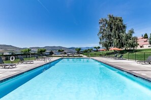 A rectangular swimming pool with a clear blue water surface, surrounded by lounge chairs and a fence. - Bright 1BR Lakefront - Patio - Pool (Chelan)