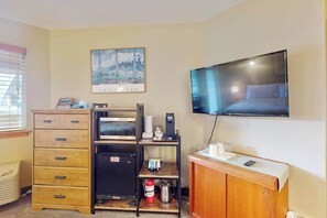 Hotelkamer met een bed, een tv aan de muur, een houten dressoir, een kleine koelkast en een koffiezetapparaat.