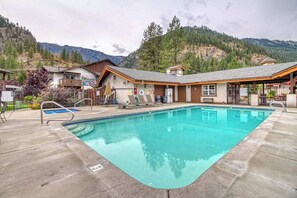 A swimming pool with a view of mountains, a covered seating area, and a building with a sloped roof. - Sunny Studio Mountainview 2nd-Floor - Balcony (Leavenworth)