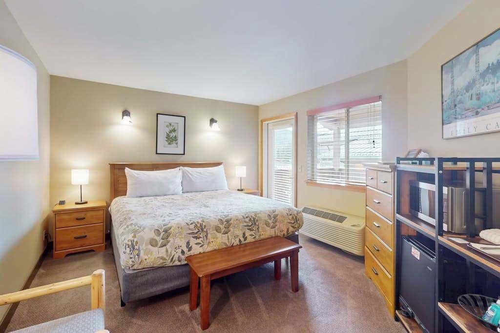 A bedroom with a bed, bedside tables, a bench, a dresser, and a radiator.