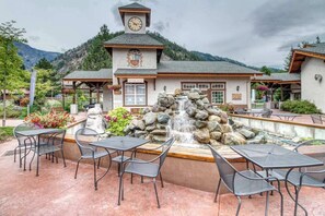 A building with a clock tower, outdoor seating, and a waterfall feature. - Sunny Studio Mountainview 2nd-Floor - Balcony (Leavenworth)
