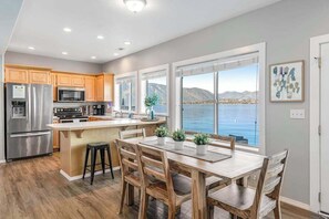 A modern kitchen with a large island, wooden cabinets, and a view of a lake.